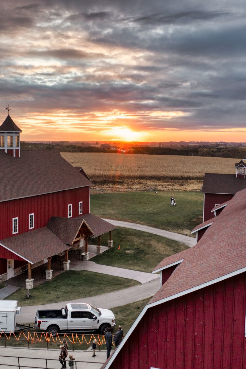 Aerial view of traditional red barns during sunset in Altura, Minnesota, showcasing rural charm.